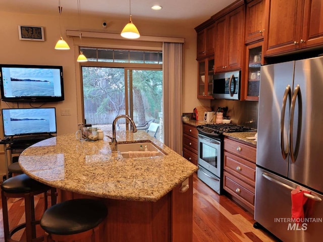 kitchen featuring a kitchen island with sink, a breakfast bar, light hardwood / wood-style flooring, stainless steel appliances, and decorative light fixtures