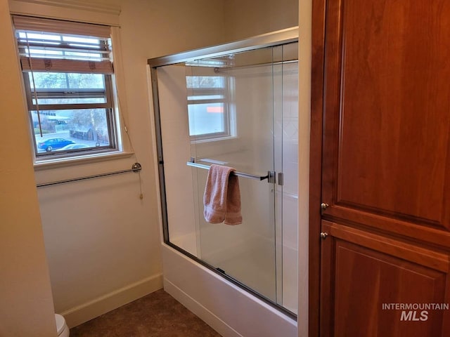 bathroom with tile floors, enclosed tub / shower combo, toilet, and a healthy amount of sunlight