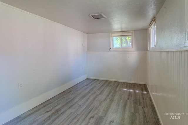 empty room with light hardwood / wood-style floors and a textured ceiling