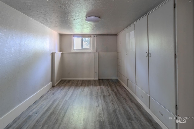 basement with hardwood / wood-style floors and a textured ceiling