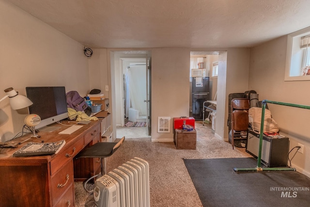 carpeted office featuring heating unit, a healthy amount of sunlight, and a textured ceiling