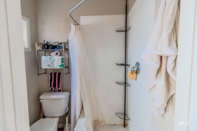 bathroom with toilet, a shower with shower curtain, and tile patterned flooring