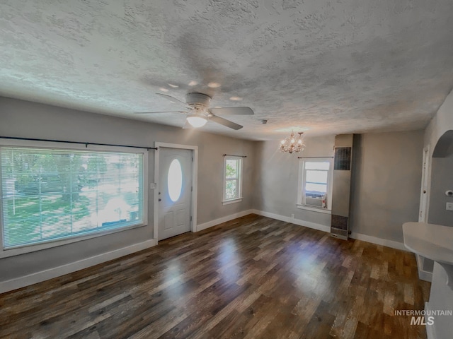 entrance foyer featuring ceiling fan with notable chandelier, a textured ceiling, a wealth of natural light, and dark hardwood / wood-style flooring