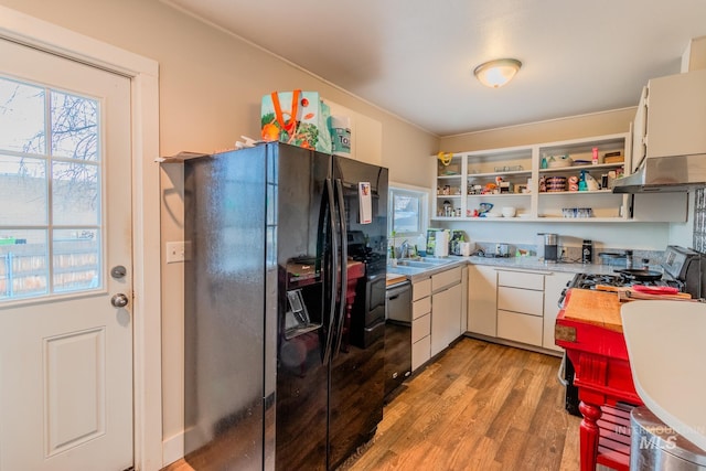 kitchen featuring black appliances, white cabinetry, light hardwood / wood-style floors, and sink