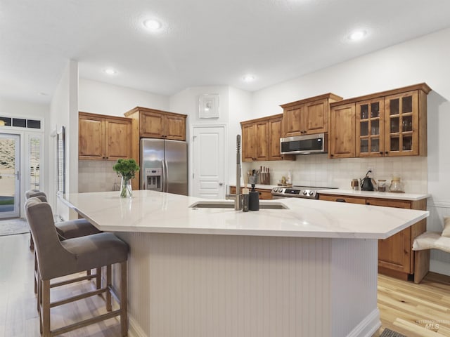 1262 N Forestdale Pl, Eagle, ID 83616 - kitchen featuring appliances with stainless steel finishes, light wood-style floors, brown cabinets, backsplash, and glass insert cabinets