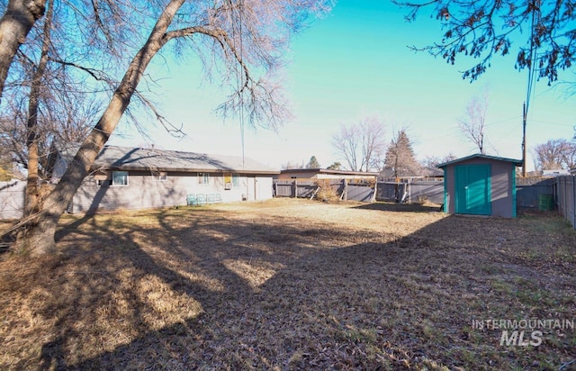 view of yard with a fenced backyard, a storage unit, and an outbuilding