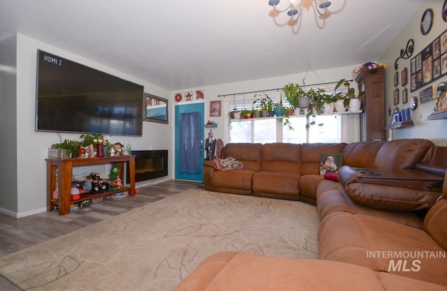 living area featuring a glass covered fireplace, a notable chandelier, and wood finished floors