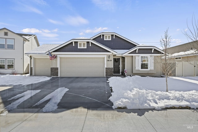 view of front of home with an attached garage, stone siding, driveway, and fence