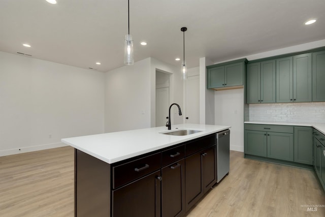 kitchen featuring sink, light hardwood / wood-style flooring, stainless steel dishwasher, an island with sink, and decorative light fixtures