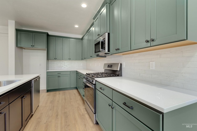 kitchen featuring green cabinets, light hardwood / wood-style floors, and appliances with stainless steel finishes