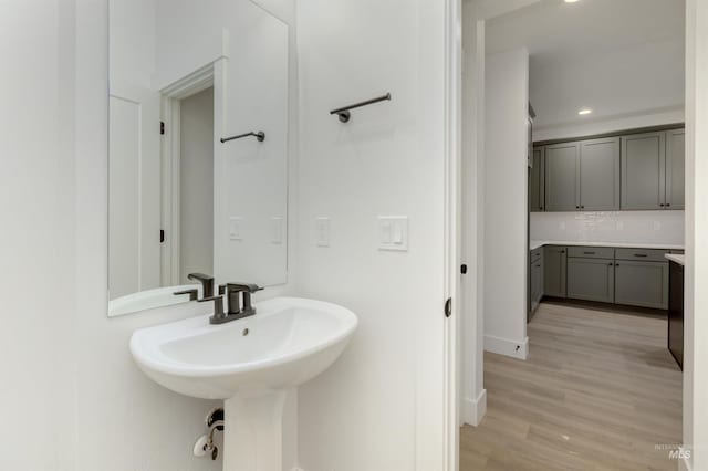 bathroom featuring hardwood / wood-style floors, decorative backsplash, and sink