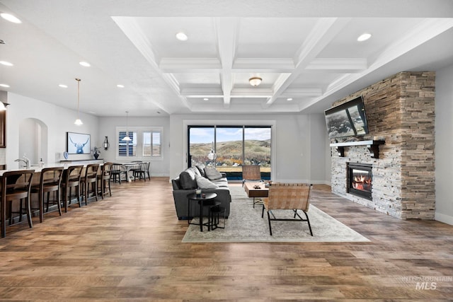 living room with a wealth of natural light, beam ceiling, wood finished floors, and a fireplace