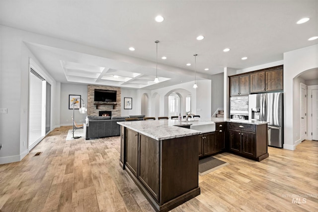 kitchen featuring dark brown cabinets, arched walkways, stainless steel refrigerator with ice dispenser, and a sink