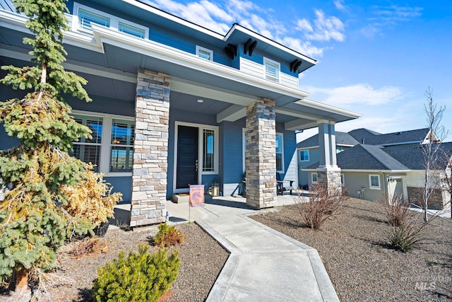 view of exterior entry featuring stone siding and covered porch