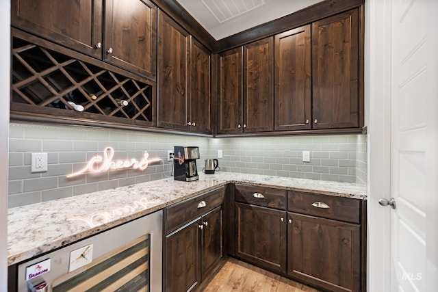 kitchen featuring tasteful backsplash, dark brown cabinetry, and light stone countertops