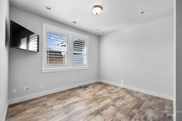 empty room with visible vents, recessed lighting, baseboards, and wood finished floors