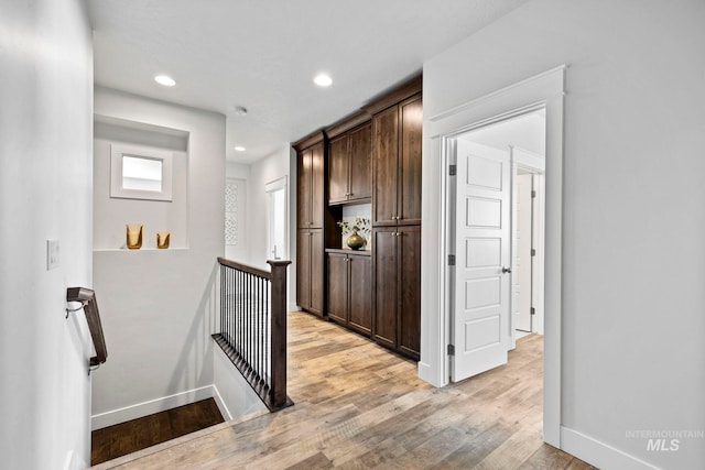 hallway with light wood-style flooring, recessed lighting, an upstairs landing, and baseboards