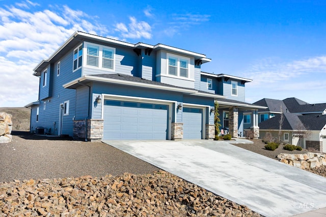 prairie-style home featuring stone siding, an attached garage, concrete driveway, and central AC