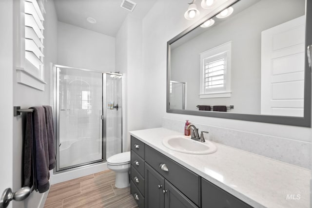 full bath featuring vanity, a shower stall, toilet, and visible vents