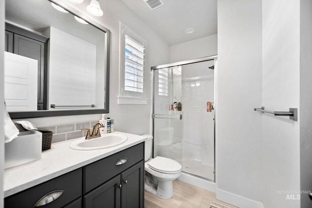 bathroom with vanity, wood finished floors, visible vents, a shower stall, and toilet