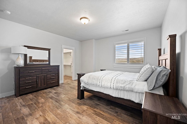 bedroom with visible vents, baseboards, and wood finished floors