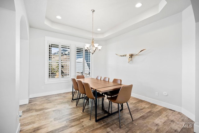 dining room featuring wood finished floors, baseboards, a tray ceiling, recessed lighting, and a chandelier