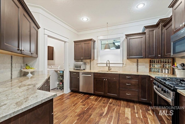 3931 N Park Crossing Ave, Meridian, ID 83646 - kitchen featuring stainless steel appliances, dark brown cabinets, dark wood-style flooring, decorative backsplash, and ornamental molding