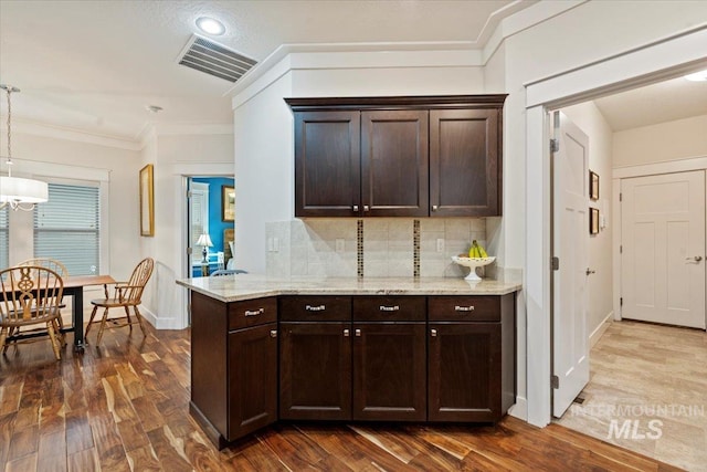 3931 N Park Crossing Ave, Meridian, ID 83646 - kitchen with dark brown cabinetry, backsplash, dark wood finished floors, light stone counters, and ornamental molding