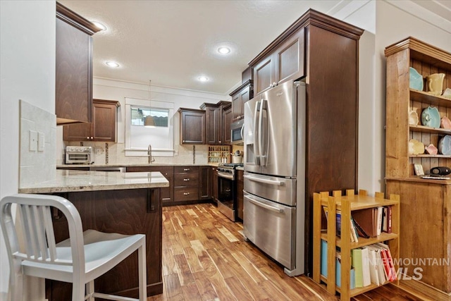 3931 N Park Crossing Ave, Meridian, ID 83646 - kitchen with stainless steel appliances, light wood-style floors, dark brown cabinetry, light stone countertops, and recessed lighting