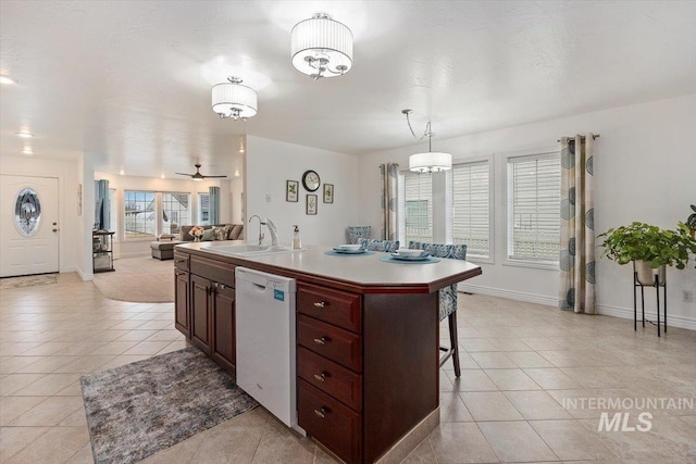 kitchen with white dishwasher, a sink, open floor plan, light countertops, and a center island with sink