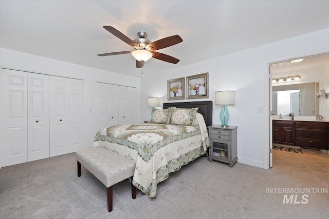 bedroom featuring multiple closets, a ceiling fan, light carpet, and ensuite bathroom