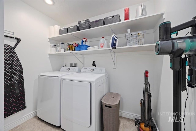 laundry area featuring laundry area, light tile patterned floors, baseboards, and washing machine and clothes dryer