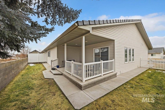 rear view of house featuring a fenced backyard and a yard