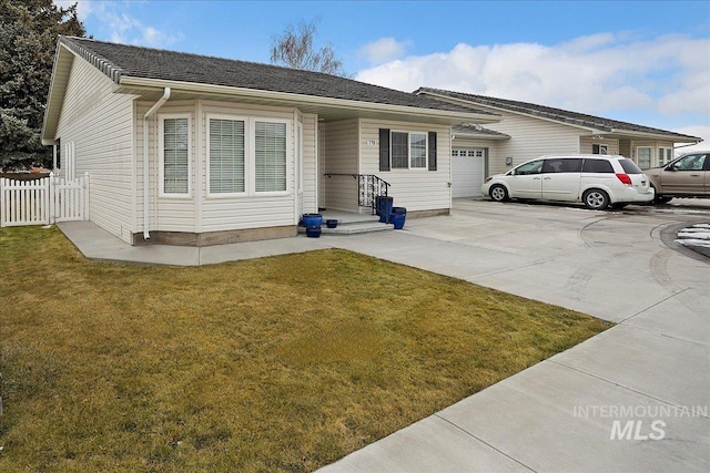 ranch-style home featuring concrete driveway, an attached garage, fence, and a front yard