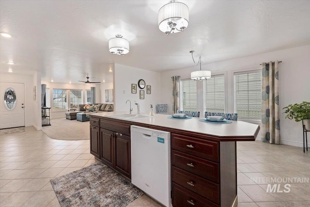 kitchen with decorative light fixtures, light countertops, open floor plan, white dishwasher, and an island with sink