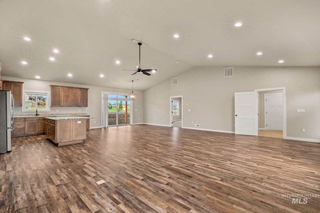 kitchen with a center island, dark hardwood / wood-style flooring, stainless steel fridge, ceiling fan, and high vaulted ceiling