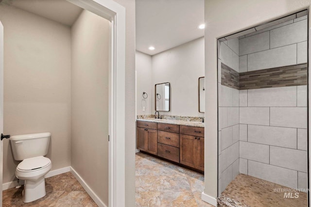 bathroom featuring vanity, toilet, and a tile shower