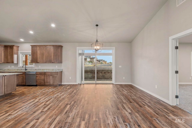 kitchen with hanging light fixtures, stainless steel dishwasher, dark wood-type flooring, light stone counters, and an inviting chandelier