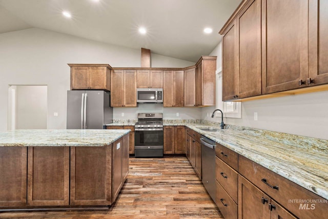 kitchen with sink, light hardwood / wood-style floors, stainless steel appliances, lofted ceiling, and light stone counters