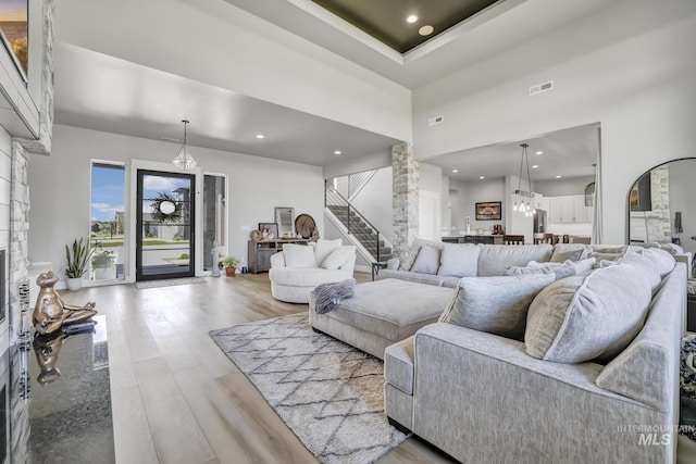 living room with arched walkways, wood finished floors, a towering ceiling, visible vents, and stairs