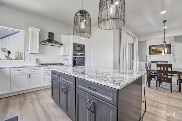 kitchen with stainless steel appliances, white cabinetry, and wall chimney range hood