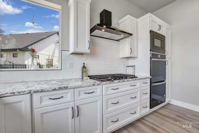 kitchen featuring built in microwave, white cabinetry, wall chimney exhaust hood, and dobule oven black