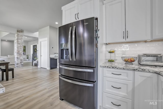 kitchen with a toaster, backsplash, white cabinets, and stainless steel fridge with ice dispenser