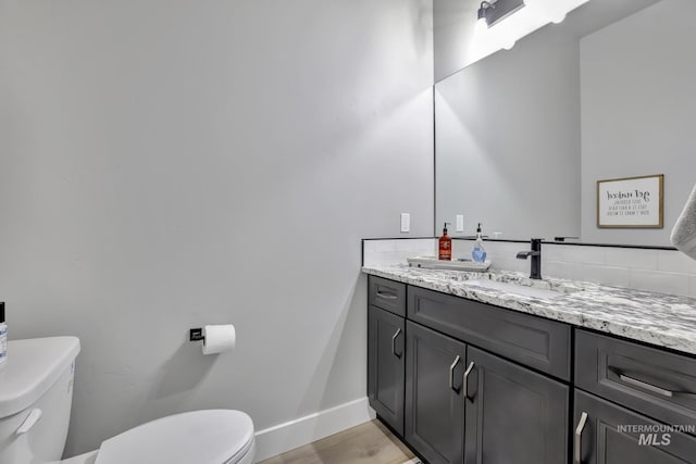 bathroom with baseboards, vanity, toilet, and wood finished floors