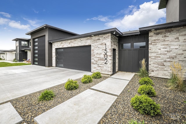 exterior space with a garage, concrete driveway, and stone siding