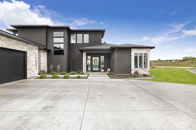 view of front facade with driveway, a garage, stone siding, a front lawn, and stucco siding