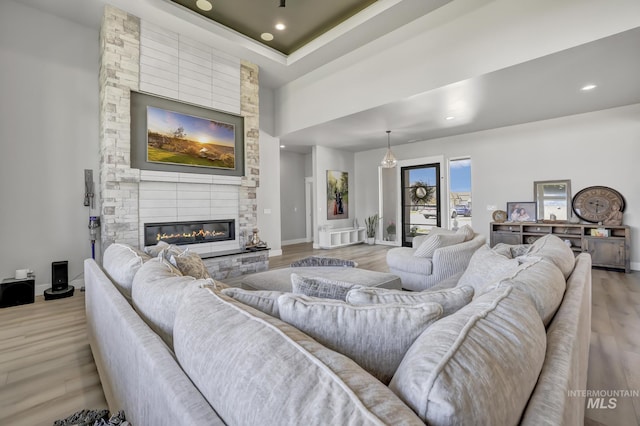 living area featuring light wood-type flooring, a fireplace, baseboards, and recessed lighting