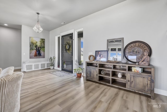 foyer with a notable chandelier, baseboards, visible vents, and light wood-style floors