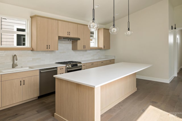 kitchen with appliances with stainless steel finishes, a sink, under cabinet range hood, and light brown cabinetry