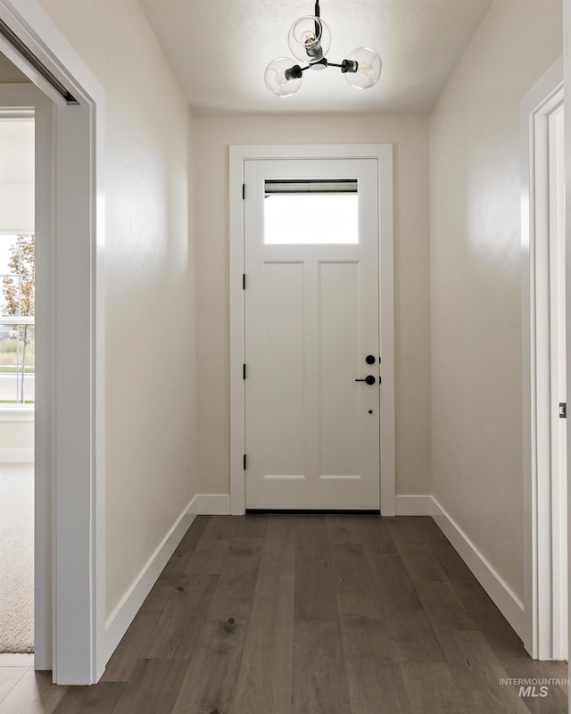 doorway featuring dark wood-type flooring and baseboards